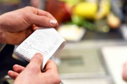 H&auml;nde mit Kassenzettel an der Kasse im Supermarkt